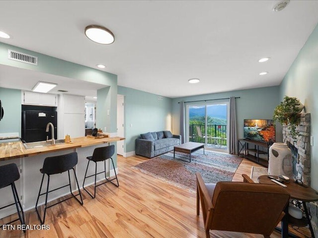 living area with visible vents, recessed lighting, and light wood-style flooring