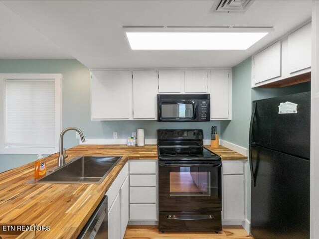 kitchen featuring a sink, white cabinetry, and black appliances