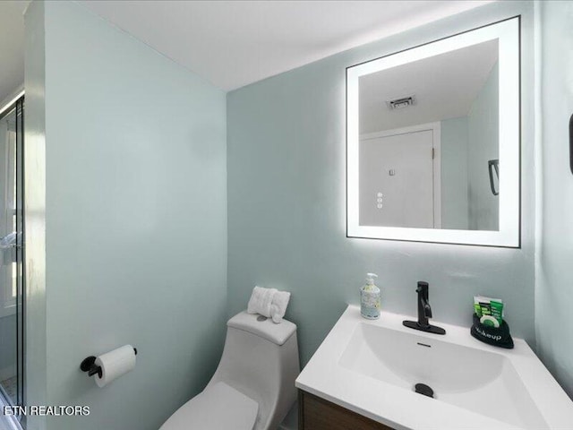 full bath featuring vanity, a shower with door, toilet, and visible vents