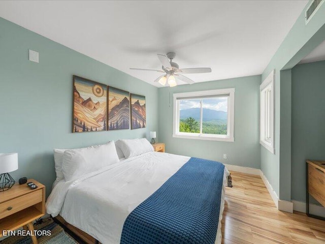 bedroom featuring visible vents, a ceiling fan, baseboards, and light wood-style floors