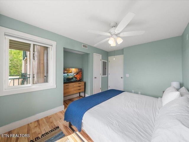 bedroom with baseboards, ceiling fan, wood finished floors, and visible vents