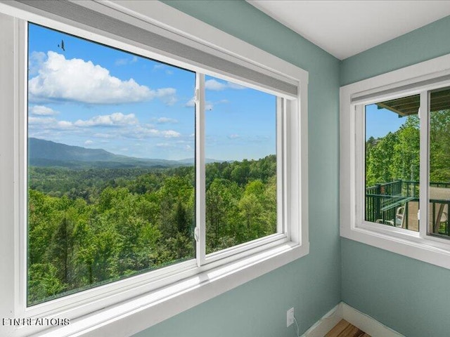 unfurnished sunroom featuring a view of trees and a mountain view