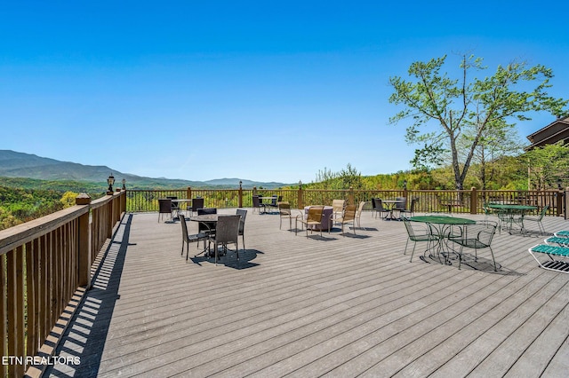 wooden terrace with outdoor dining area and a mountain view