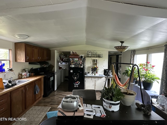 kitchen with dark wood finished floors, gas stove, light countertops, vaulted ceiling, and a sink