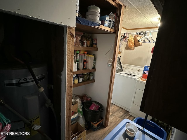 laundry room featuring water heater, wood finished floors, washing machine and clothes dryer, and laundry area
