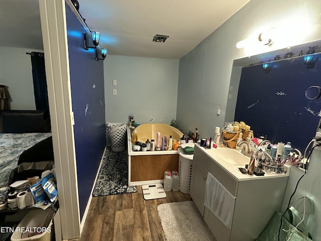 bathroom with a garden tub, vanity, and wood finished floors