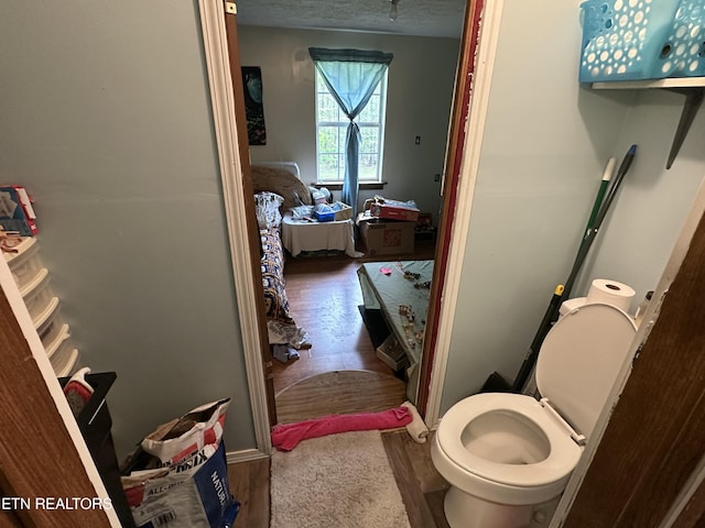 bathroom featuring wood finished floors, toilet, and ensuite bathroom