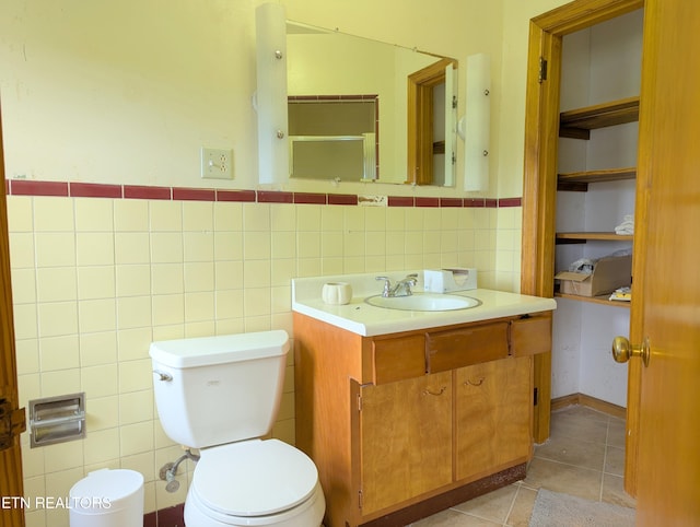 bathroom featuring toilet, tile walls, tile patterned floors, vanity, and wainscoting