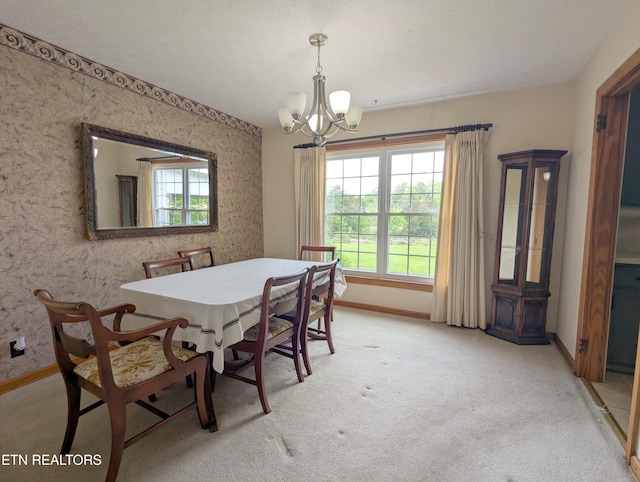 dining area with a chandelier, baseboards, and light colored carpet