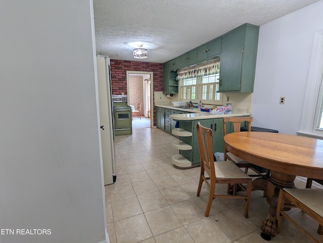 kitchen with light tile patterned floors, open shelves, light countertops, green cabinets, and a textured ceiling