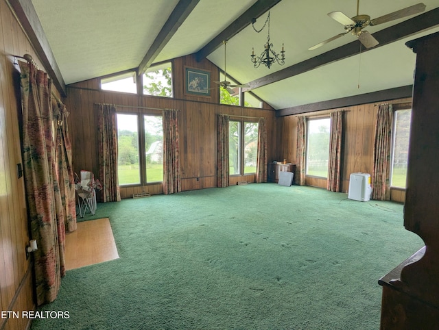interior space featuring a healthy amount of sunlight, lofted ceiling with beams, a ceiling fan, and wooden walls