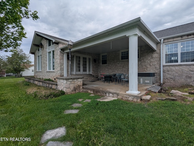 rear view of house featuring a patio, french doors, a yard, and stone siding