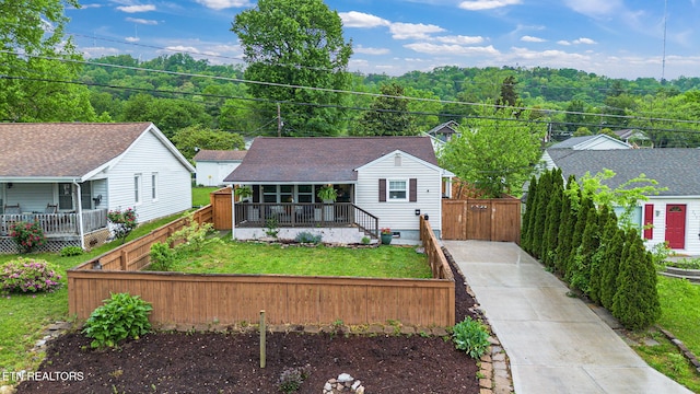 bungalow featuring concrete driveway, a front lawn, fence private yard, and covered porch