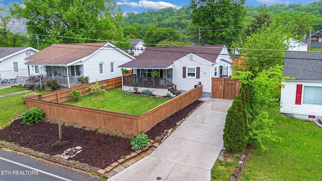 view of front facade featuring fence private yard, a porch, a front lawn, and concrete driveway