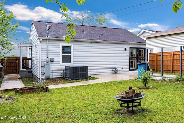 back of house with a fenced backyard, a fire pit, a yard, and cooling unit