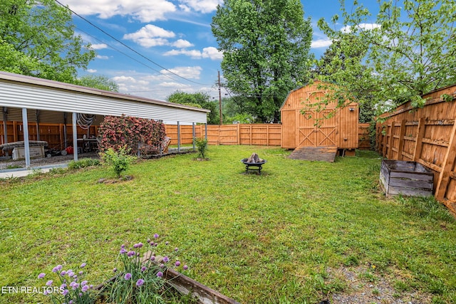 view of yard featuring a fenced backyard, an outbuilding, a storage unit, and a fire pit