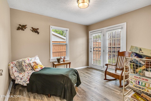 bedroom featuring baseboards, wood finished floors, a textured ceiling, and access to exterior