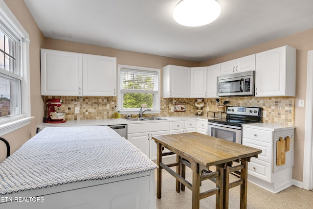 kitchen featuring decorative backsplash, a sink, white cabinetry, and appliances with stainless steel finishes