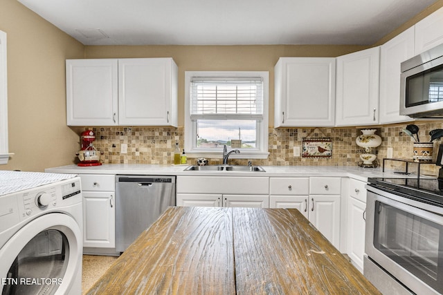 kitchen with white cabinetry, appliances with stainless steel finishes, a sink, and washer / clothes dryer