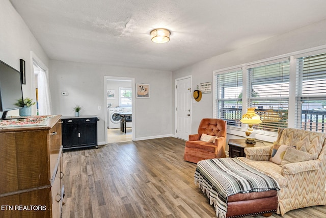 living area with baseboards, wood finished floors, and washer / dryer