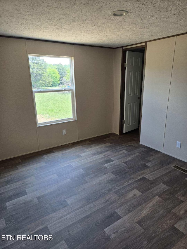 spare room with a textured ceiling and dark wood-type flooring