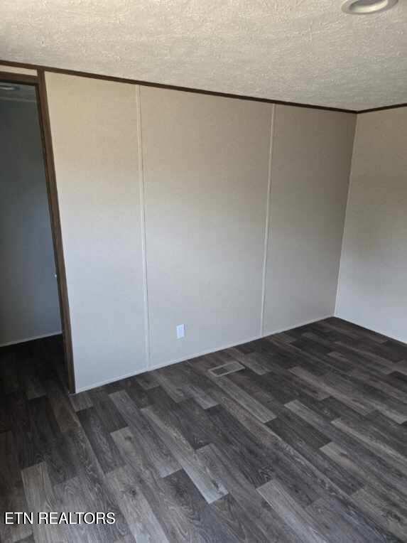 unfurnished room with a textured ceiling and wood finished floors