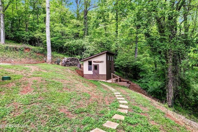 view of yard with an outdoor structure and a wooded view