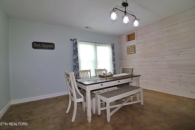 dining space with baseboards, visible vents, and wooden walls