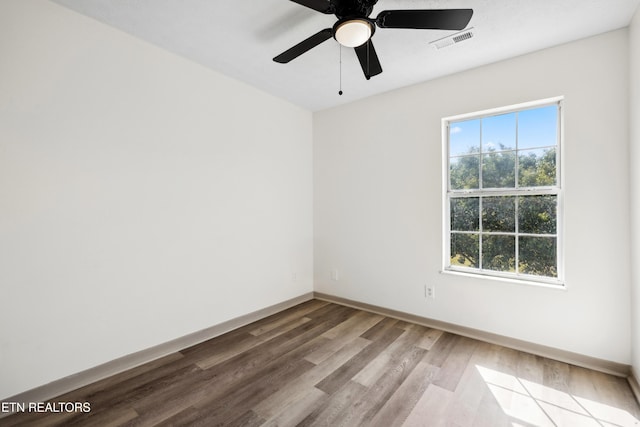 empty room with wood finished floors, visible vents, a ceiling fan, and baseboards