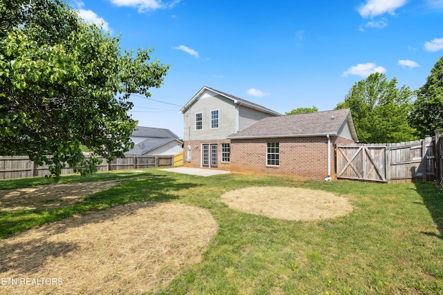 back of property with a fenced backyard, a shingled roof, a patio area, a lawn, and brick siding