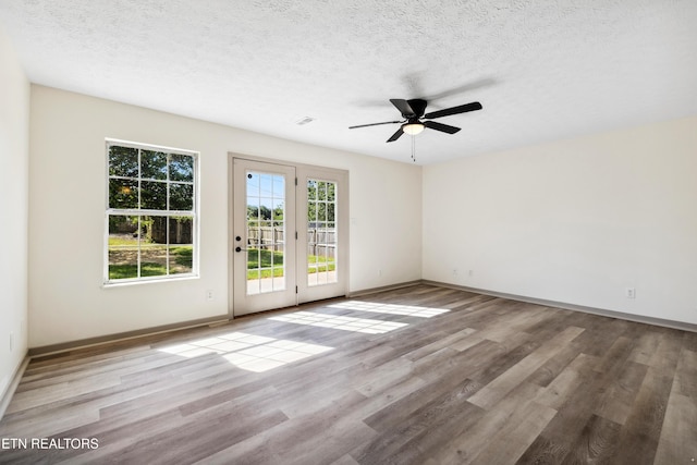 unfurnished room featuring baseboards, a ceiling fan, wood finished floors, and a textured ceiling
