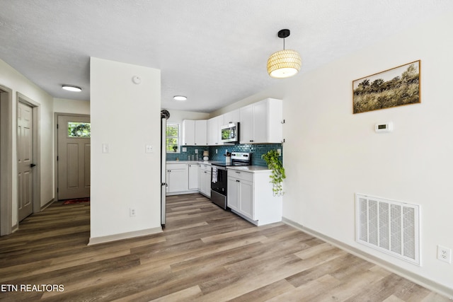 kitchen with white cabinetry, wood finished floors, stainless steel appliances, and visible vents