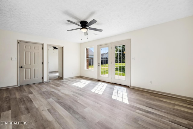 unfurnished room with wood finished floors, a textured ceiling, baseboards, and ceiling fan
