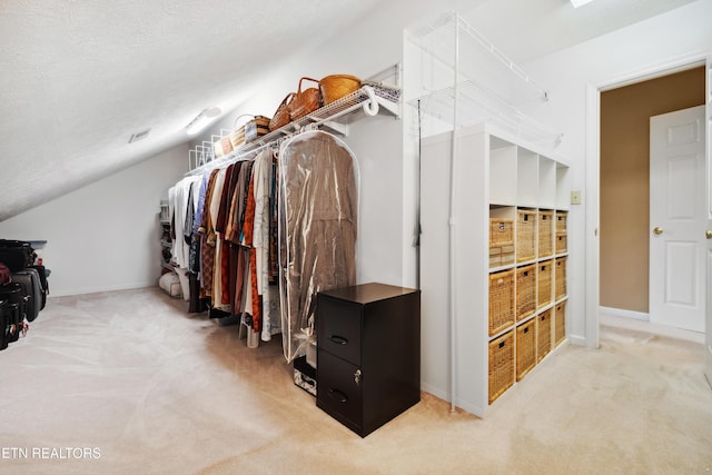 walk in closet featuring carpet flooring and vaulted ceiling