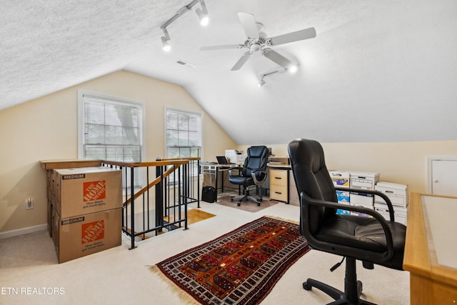 carpeted office space with track lighting, visible vents, ceiling fan, and vaulted ceiling