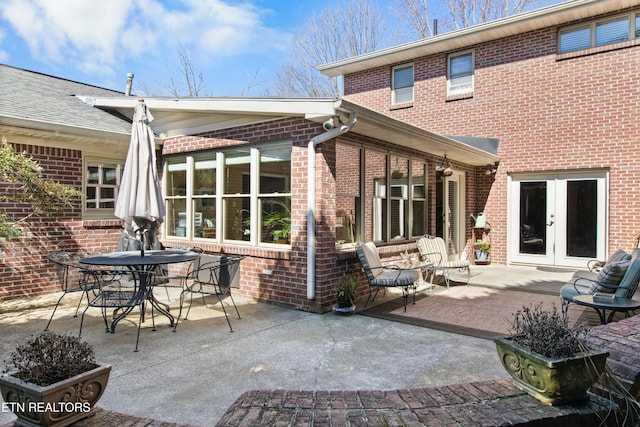 rear view of house featuring french doors, outdoor dining space, a patio, and brick siding