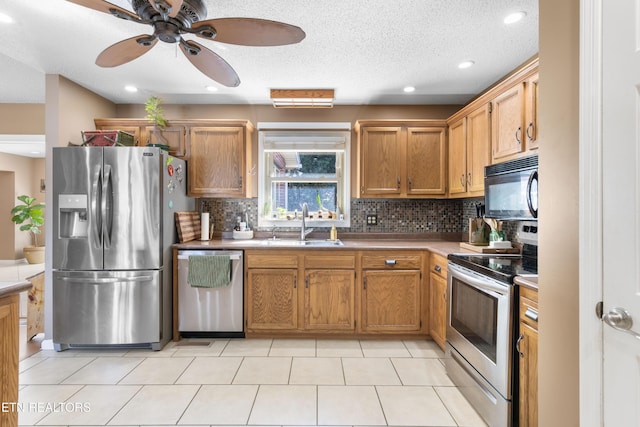 kitchen featuring ceiling fan, appliances with stainless steel finishes, decorative backsplash, and a sink