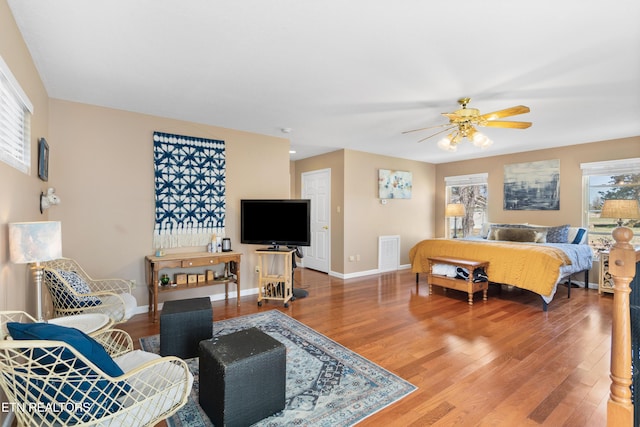 bedroom featuring wood finished floors, baseboards, visible vents, and multiple windows