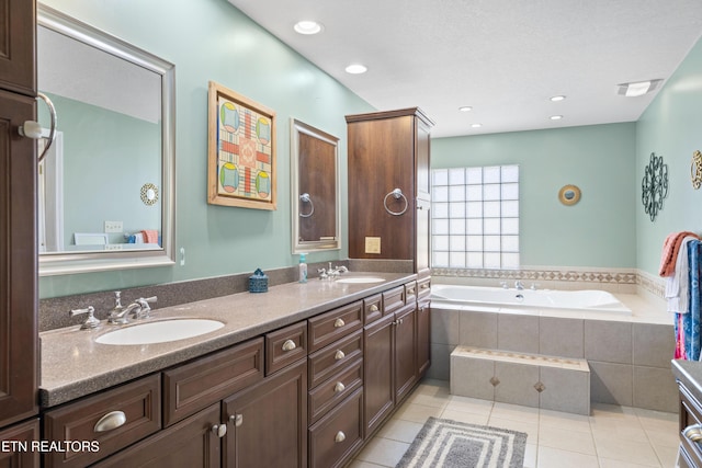 full bathroom featuring tile patterned floors, a garden tub, double vanity, and a sink
