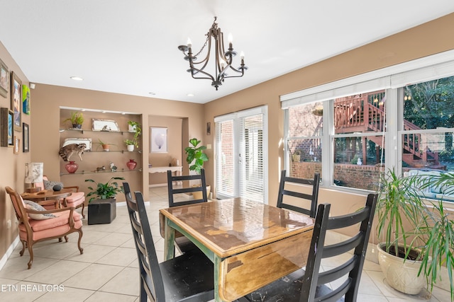 dining area featuring light tile patterned floors, a chandelier, and baseboards
