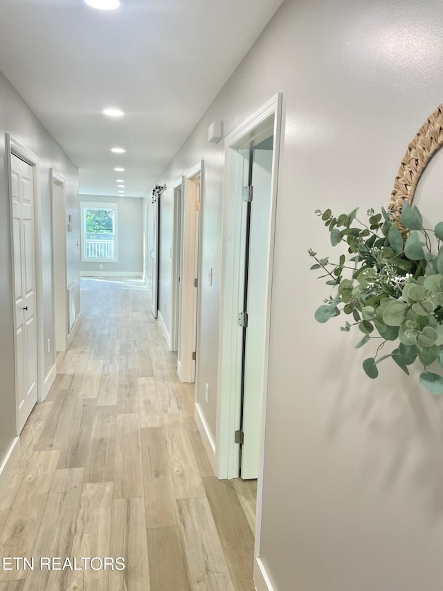 corridor with light wood finished floors and baseboards