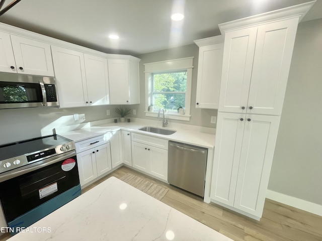 kitchen featuring recessed lighting, light wood-style floors, appliances with stainless steel finishes, white cabinets, and a sink
