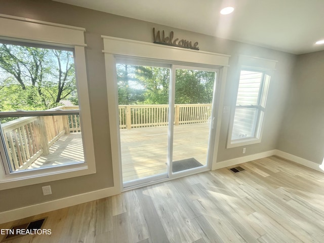 doorway with baseboards, visible vents, wood finished floors, and recessed lighting