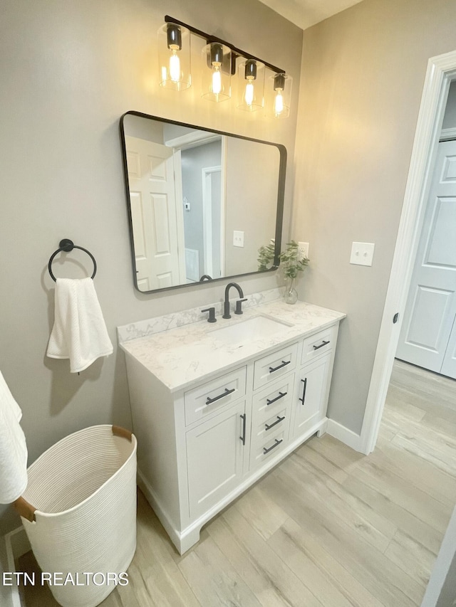 bathroom with baseboards, wood finished floors, and vanity