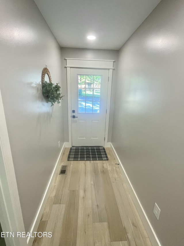 doorway featuring light wood-style floors, visible vents, and baseboards