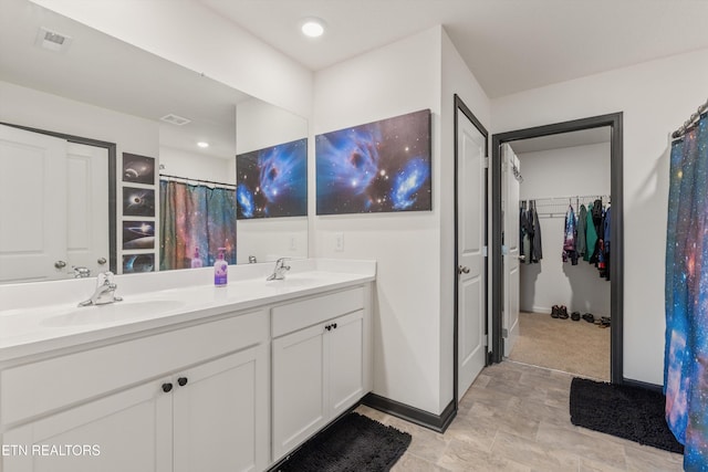 bathroom with a sink, baseboards, double vanity, and visible vents