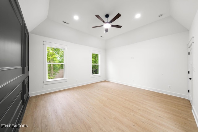 interior space with a ceiling fan, baseboards, lofted ceiling, light wood-type flooring, and visible vents