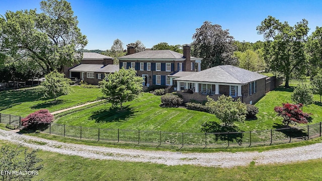 view of front of home featuring a chimney, fence, and a front yard