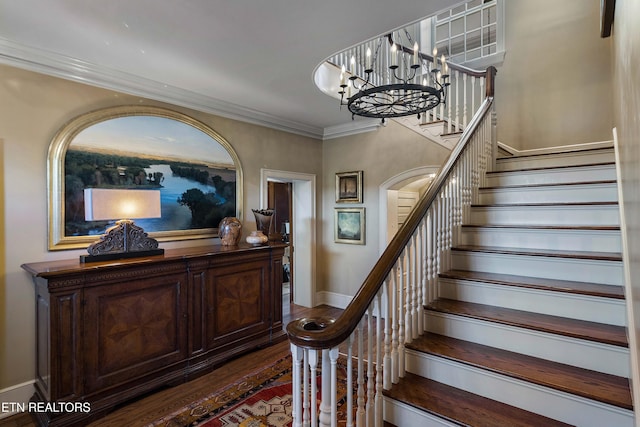 stairway featuring crown molding, an inviting chandelier, wood finished floors, and baseboards