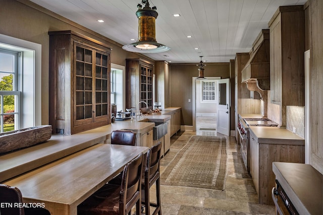 kitchen with recessed lighting, light countertops, stone finish flooring, a sink, and baseboards